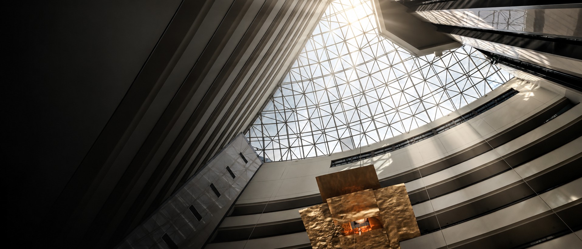 Architectural photograph by Stavros Marmaras, looking up through a sculptural interior towards a glass roof.